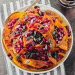overhead view of a white plate filled with roasted pumpkin and topped with pumpkin seeds and pomegranates seeds