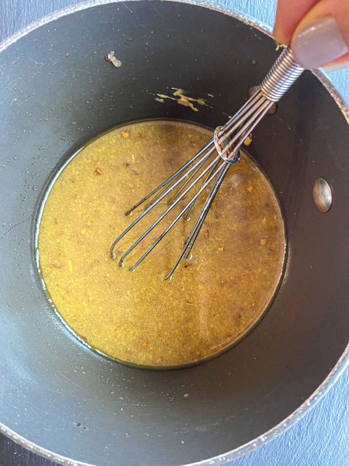 Warm pomegranate vinaigrette in a sauce pan with a whisk