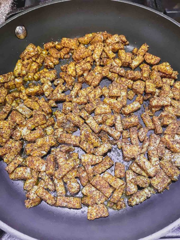 Tempeh bacon bits with spices on a skillet before cooking