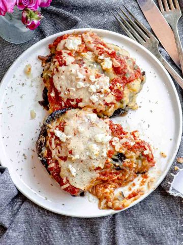 two mashed potato stuffed portobello mushrooms topped with marinara sauce and melted cheese
