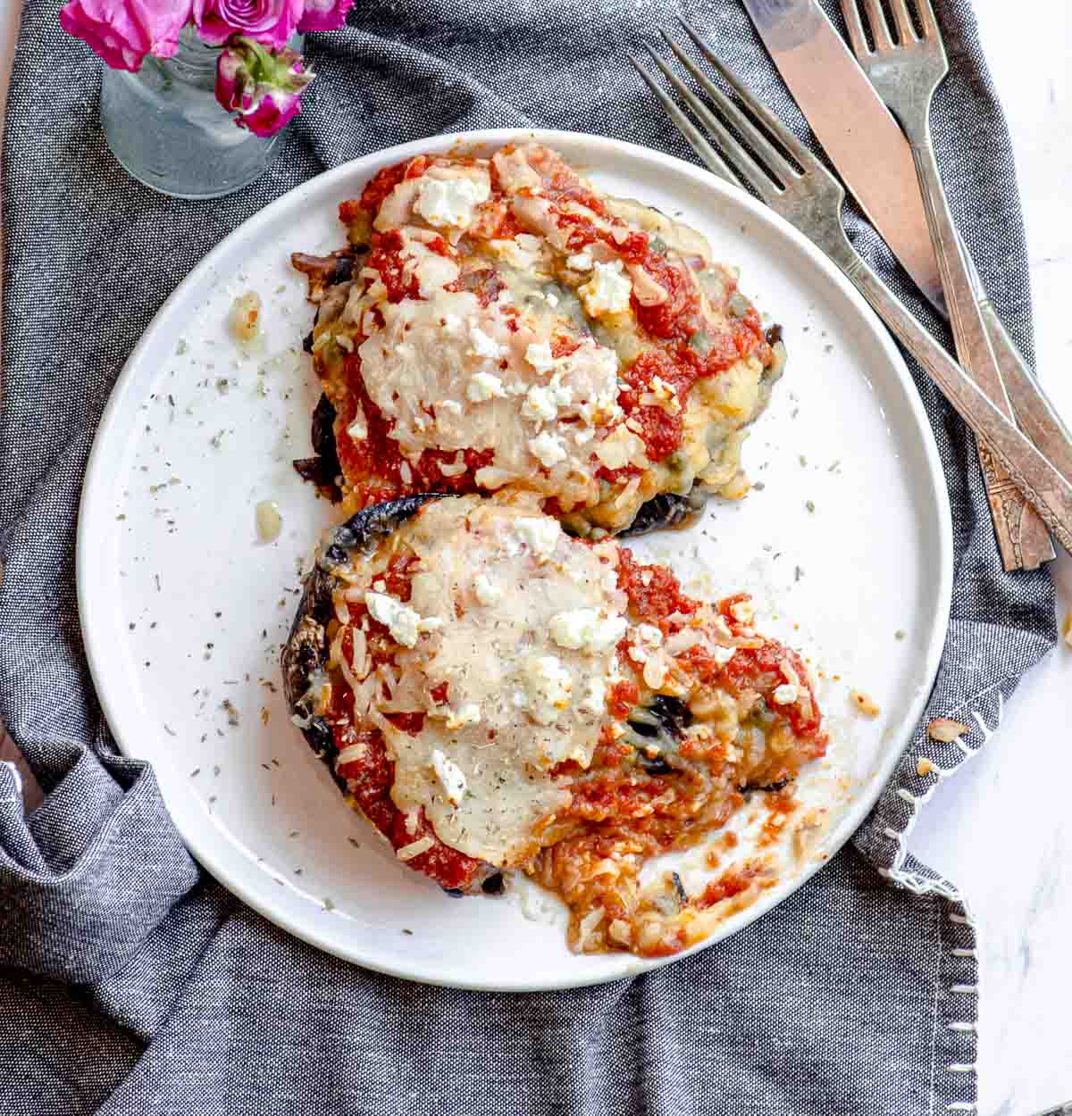 two mashed potato stuffed portobello mushrooms topped with marinara sauce and melted cheese