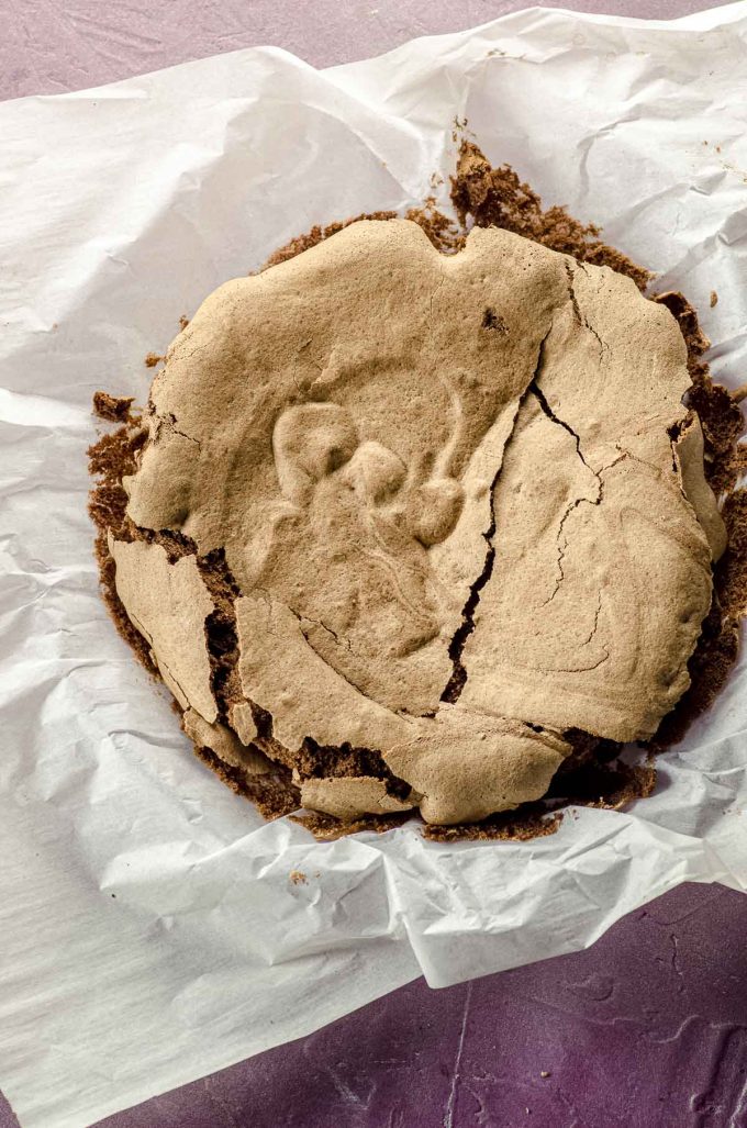 Overhead view of a flourless chocolate cake dusted on a round pan lined with parchment paper