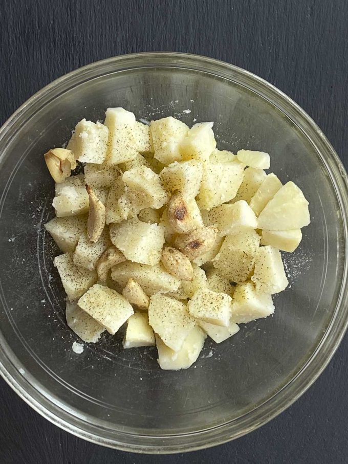 cooked diced potatoes with roasted garlic, salt, and pepper, in a bowl