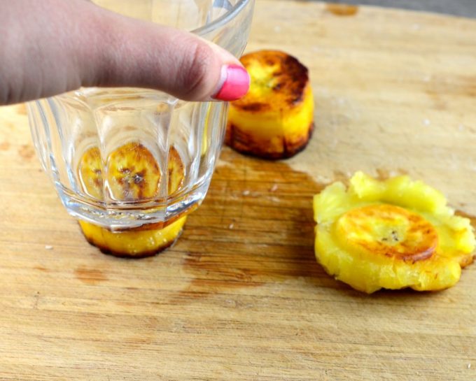 smashing a cook plantain slice with a glass