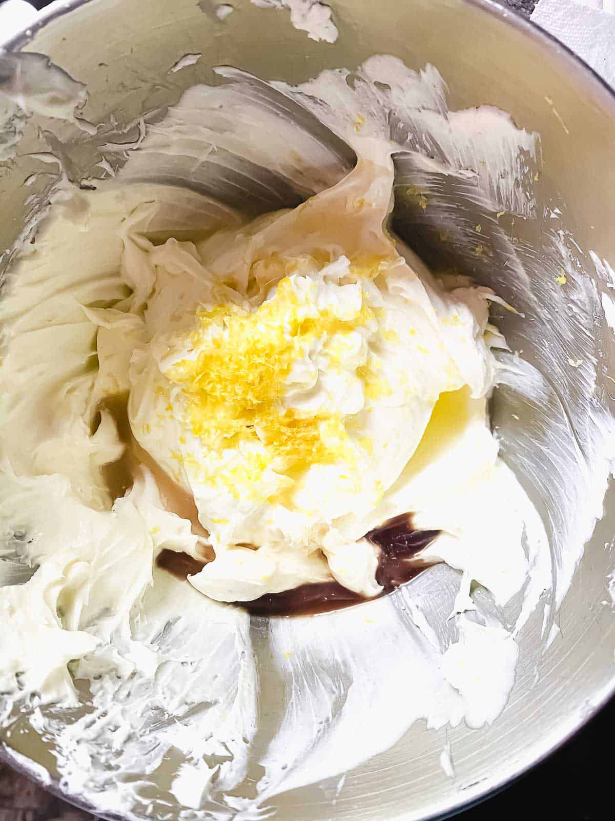 Adding lemon and lemon zest to cream cheese in a mixer bowl