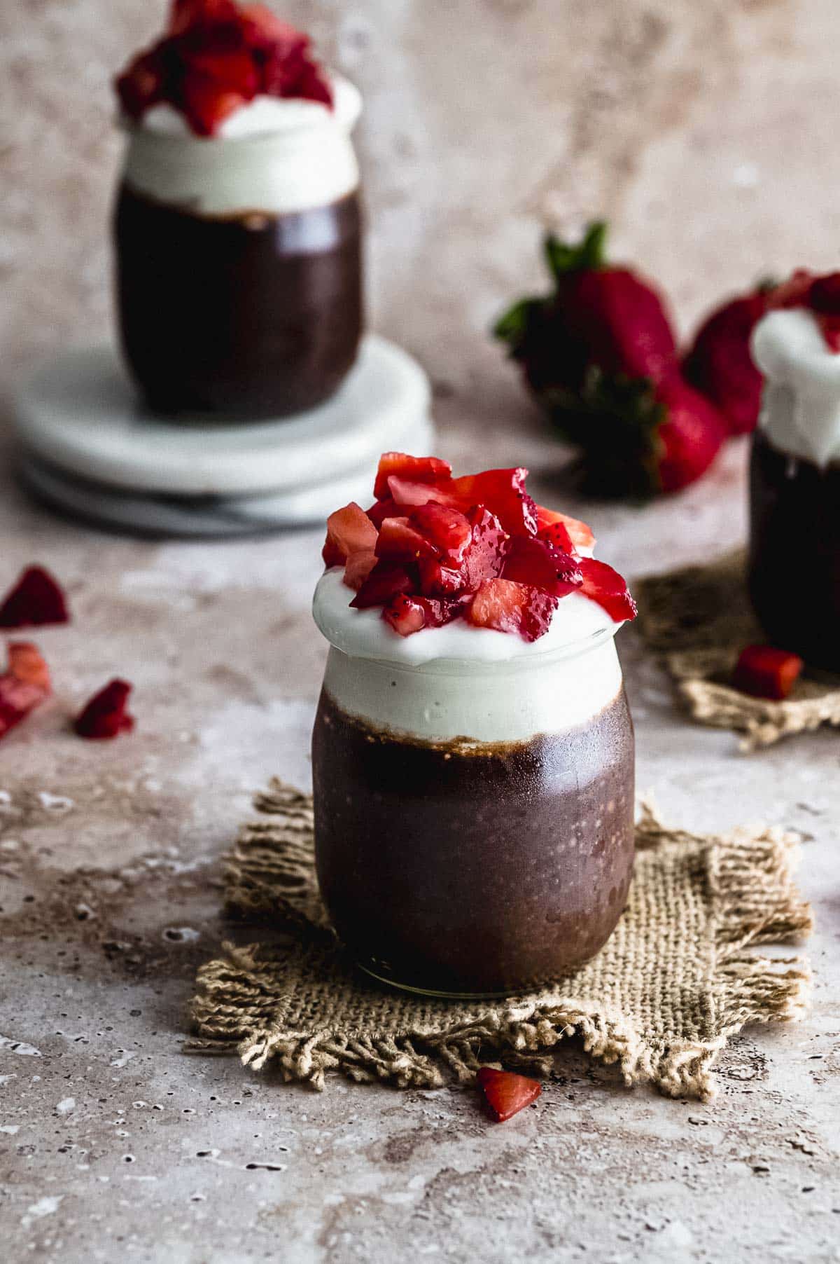 CLose up view of a small glass jar filled with chocolate chia pudding
