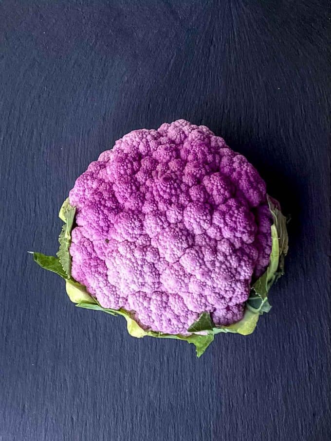 A purple cauliflower on a black surface