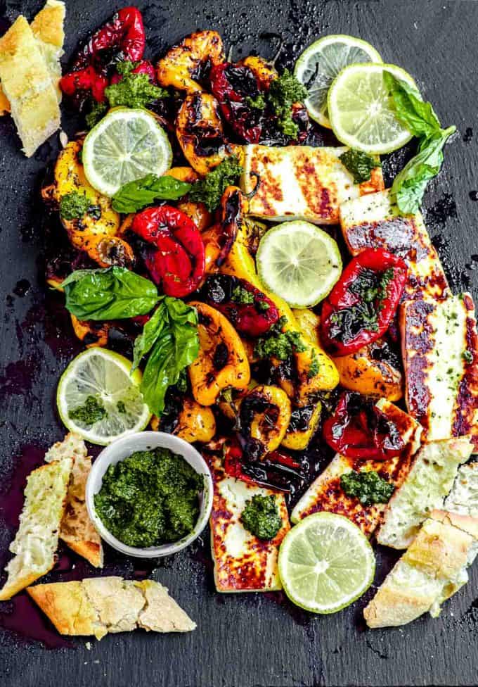 A board of sweet roasted peppers with sliced baguette, pesto and grilled halloumi cheese