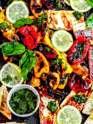 A board of sweet roasted peppers with sliced baguette, pesto and grilled halloumi cheese