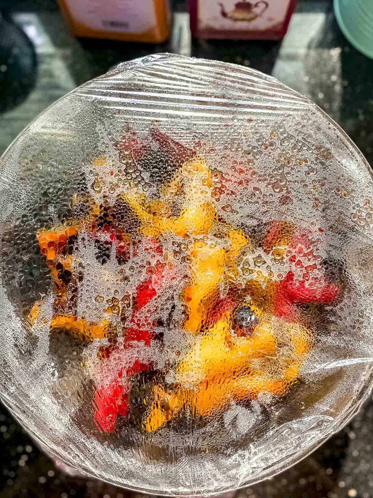 a bowl of grilled mini sweet peppers covered with plastic wrap