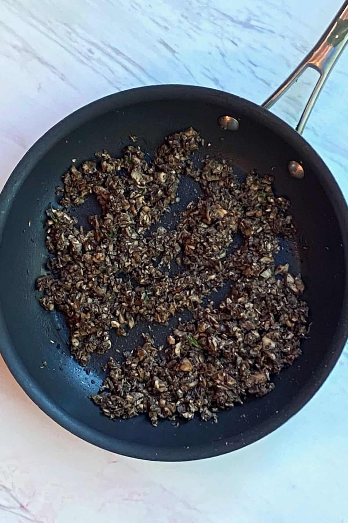 An overhead view of a pan with processed mushrooms and spices
