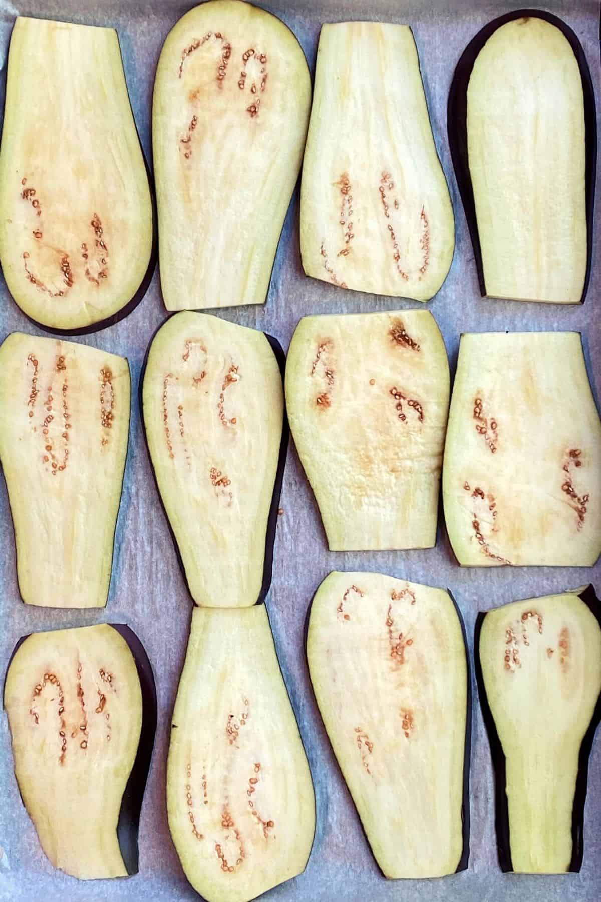 An overhead view of a parchment paper lined cookie sheet with eggplant slices