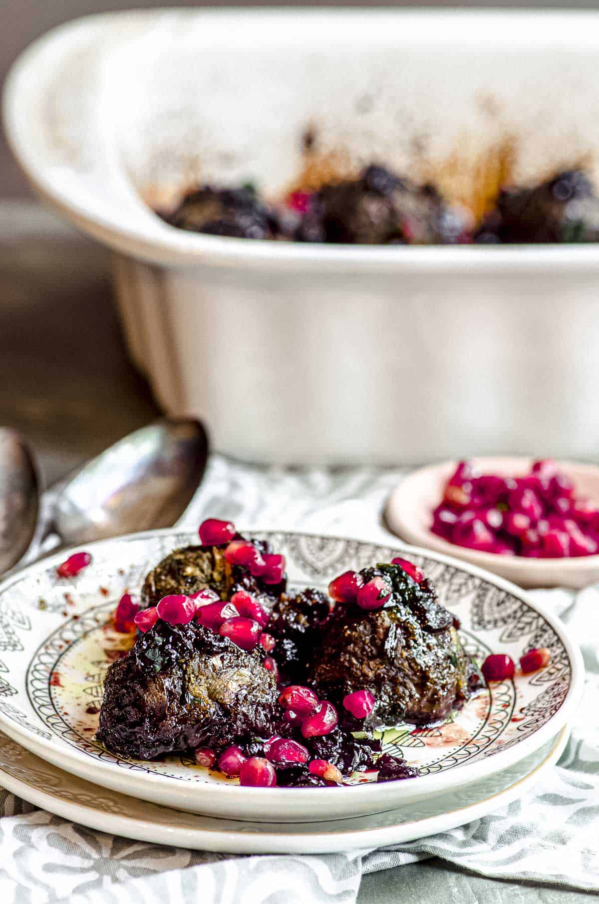 side view of three eggplant meatballs on a plate topped with pomegranate seeds