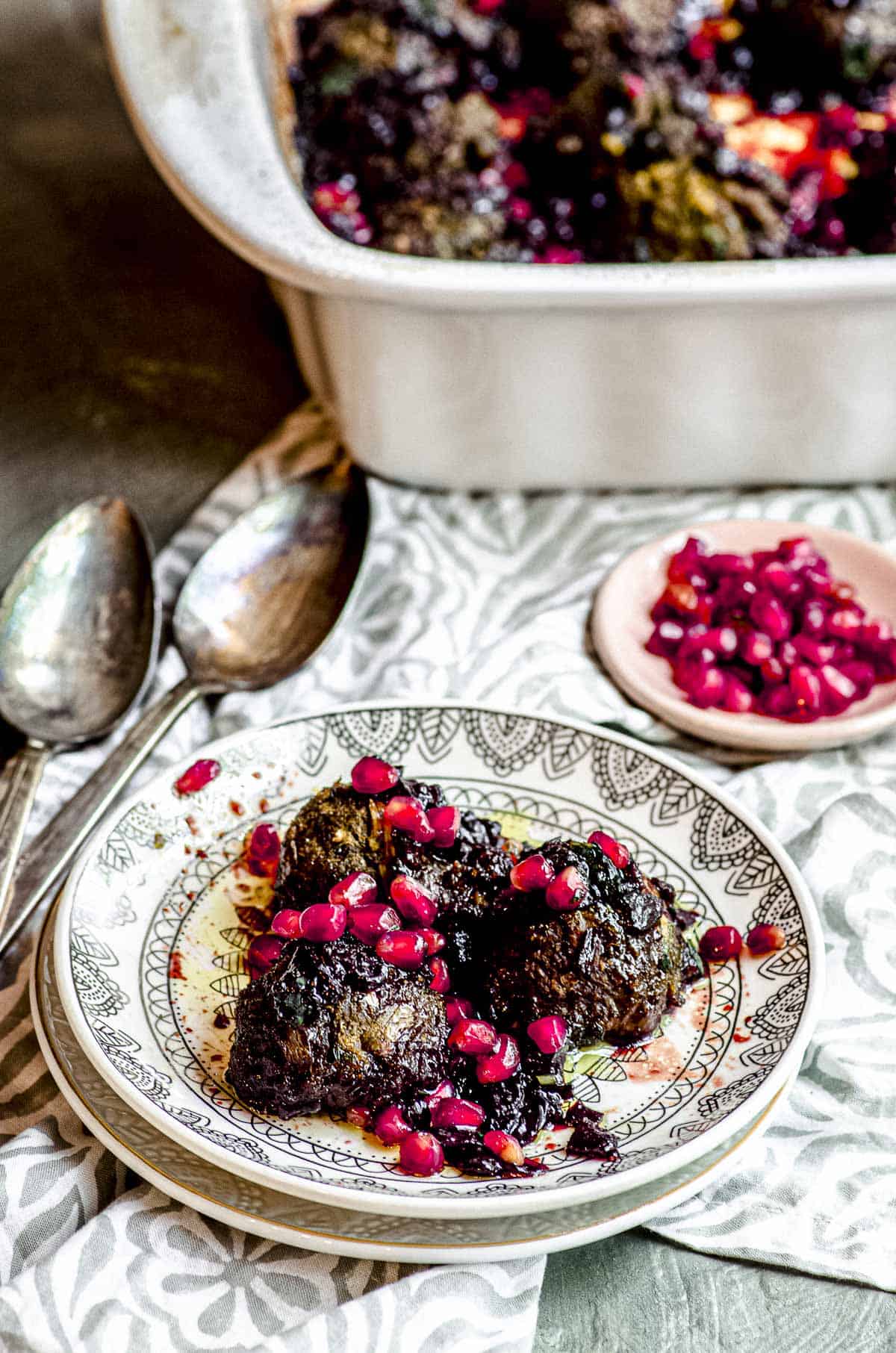 three eggplant meatballs on a plate topped with pomegranate seeds