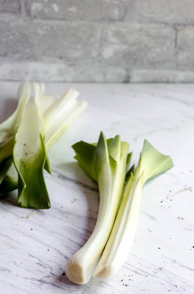 A trimmed leek cut in half with some outer leaves removed