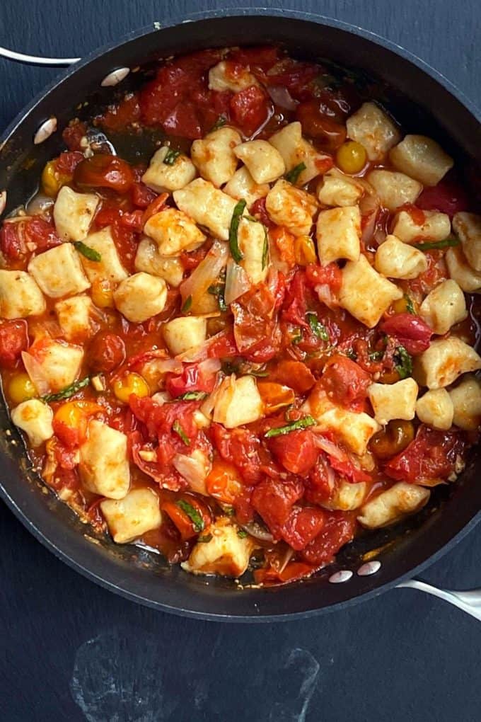 An overhead view of finished sauce with gnocchi added