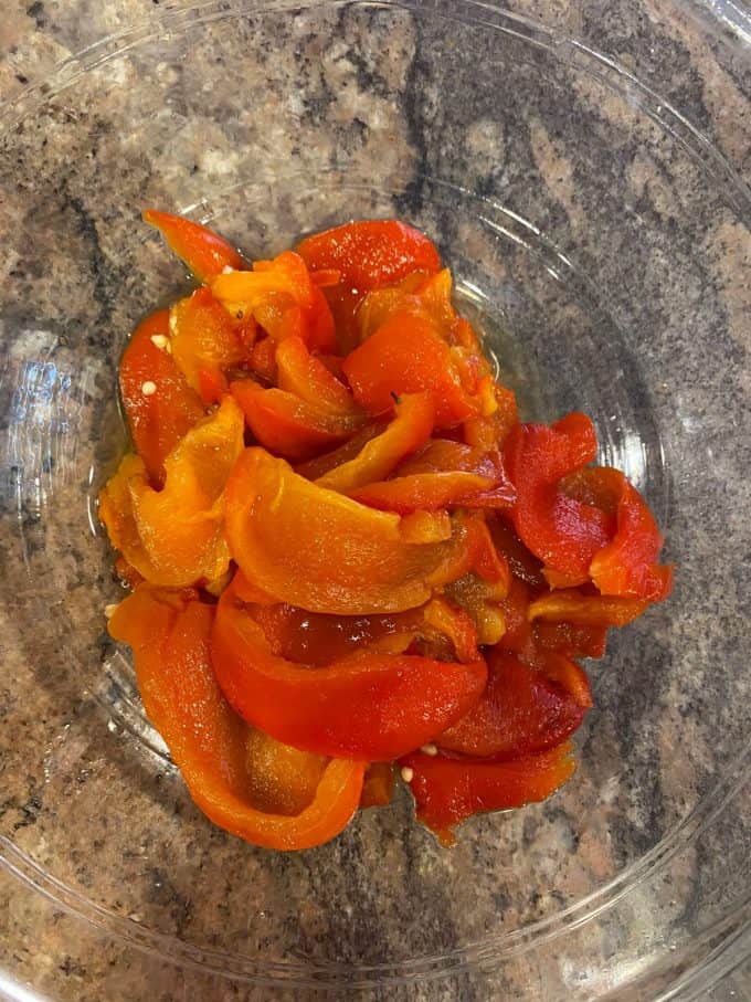 A view of roasted red pepper cut into slices in a glass bowl