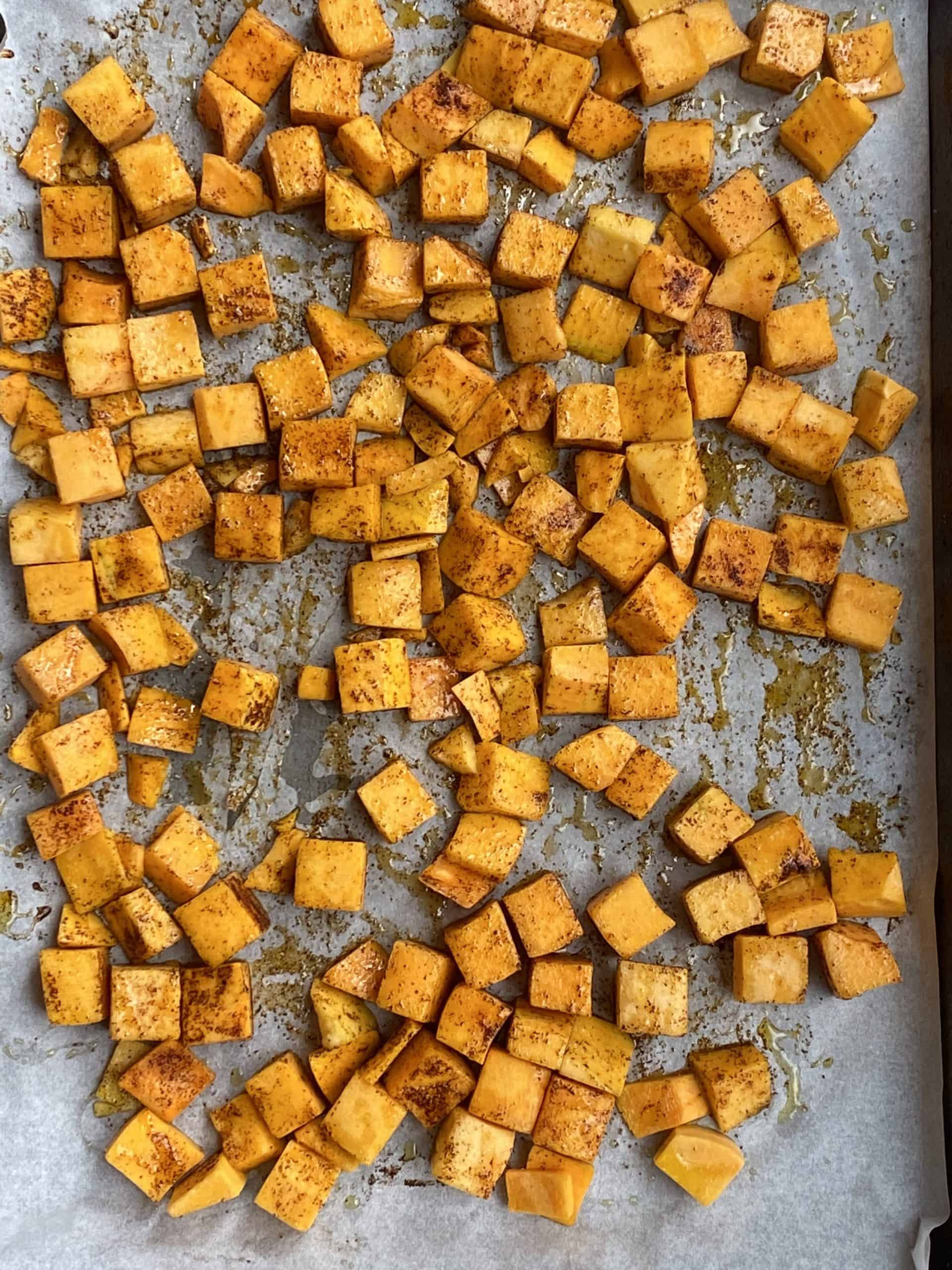 cooked butternut squash cubes on a baking sheet