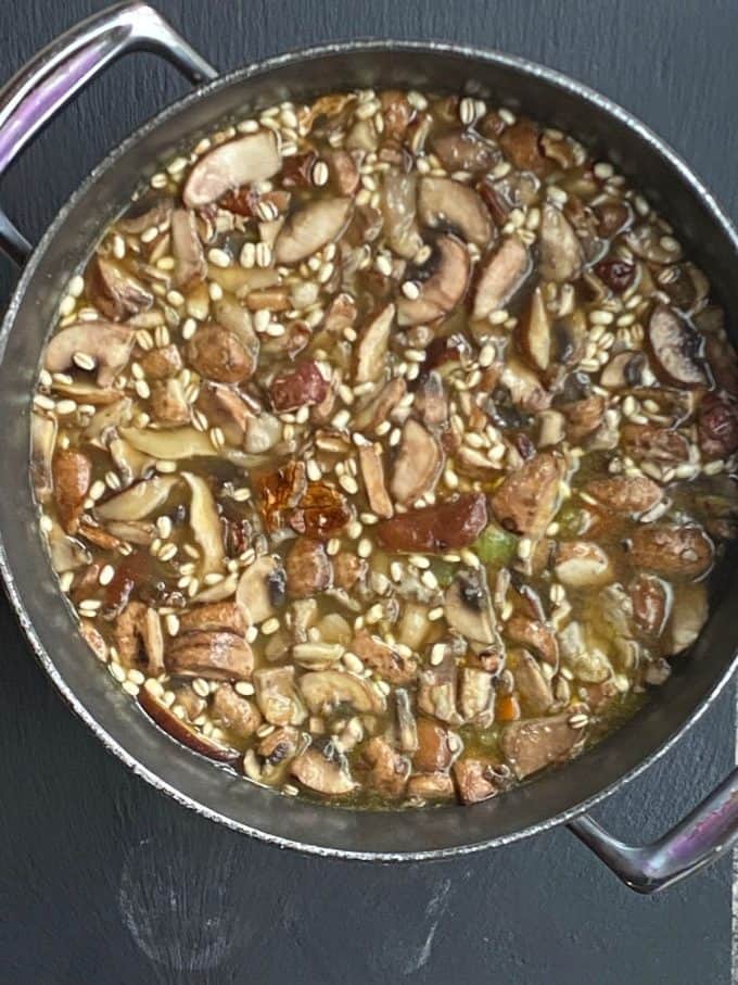 An overhead view of mushroom barley soup in a large pot