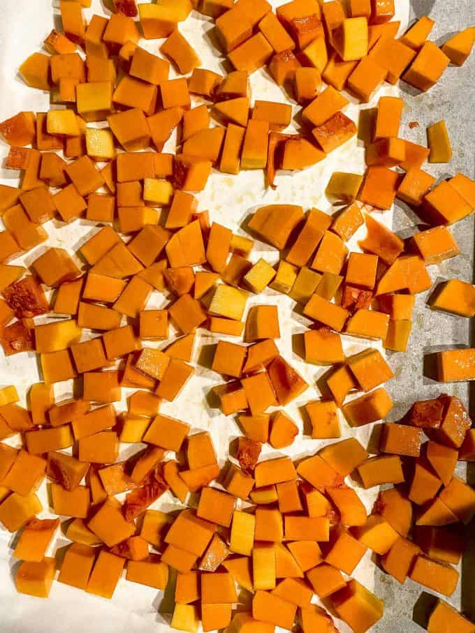 Cubed butternut squash on a parchment paper lined baking sheet