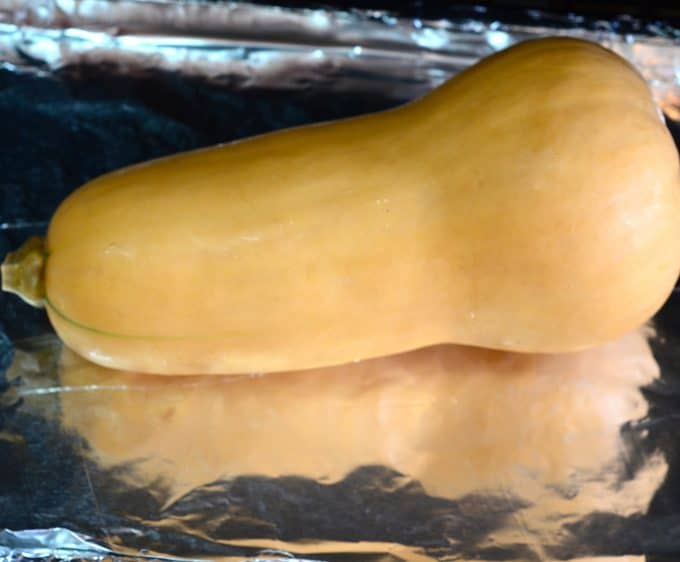 Whole butternut squash on a foil lined baking sheet