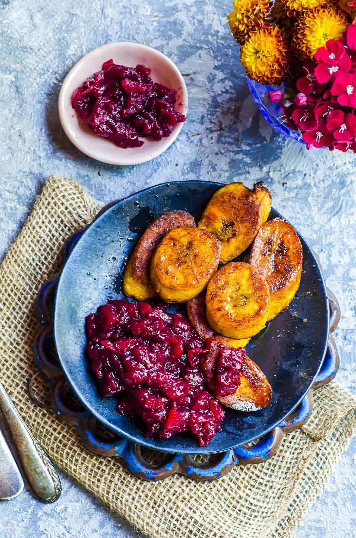 A black plate with fried plantains and cranberry sauce