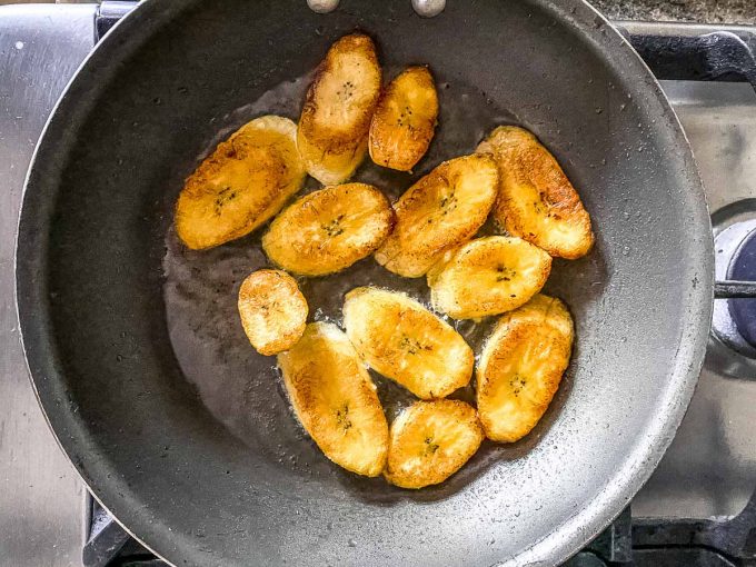 An overhead view of fried plantains being sauteed in a pan
