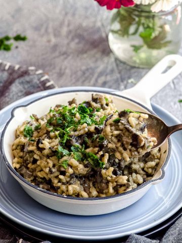 An angled view of mushroom risotto in a bowl with a spoonful placed above