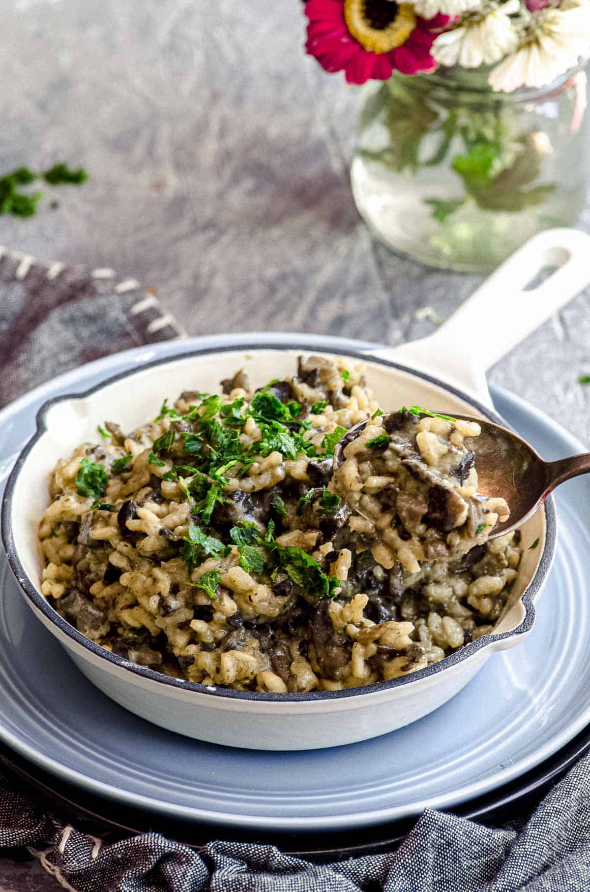 An angled view of mushroom risotto in a bowl with a spoonful placed above