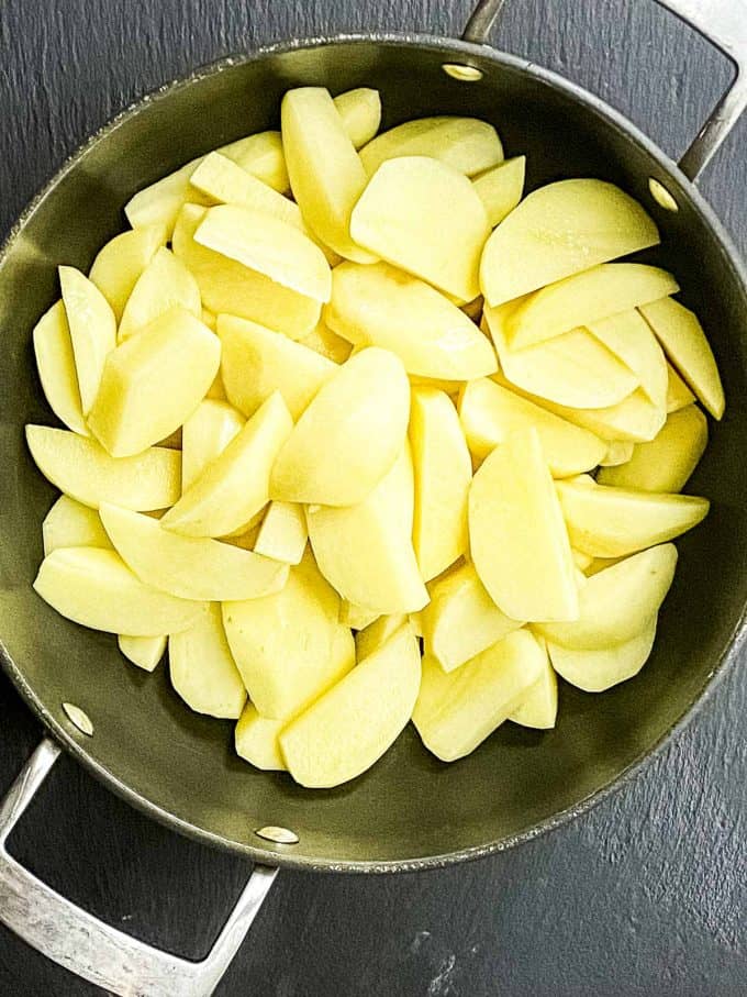 An overhead view of a pot with potato wedges to be boiled