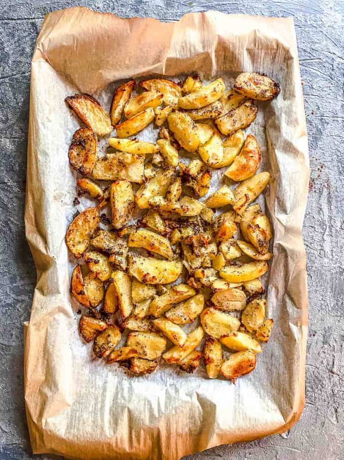 An overhead view of a parchment lined baking sheet with roasted potatoes