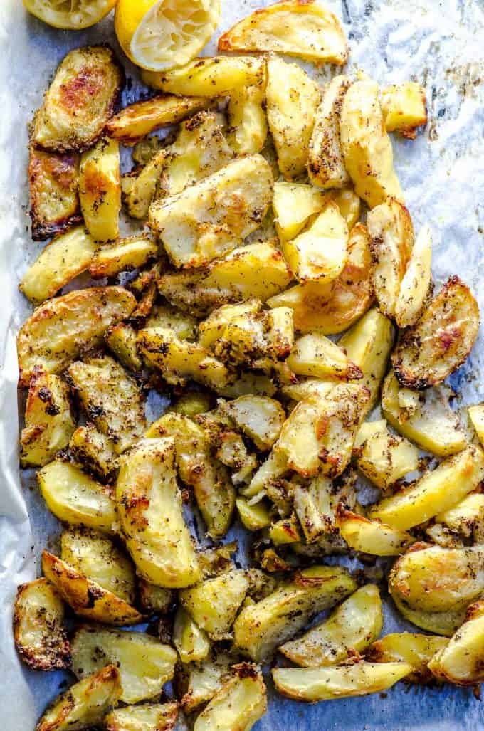 An overhead view of a parchment lined baking sheet with roasted potato wedges