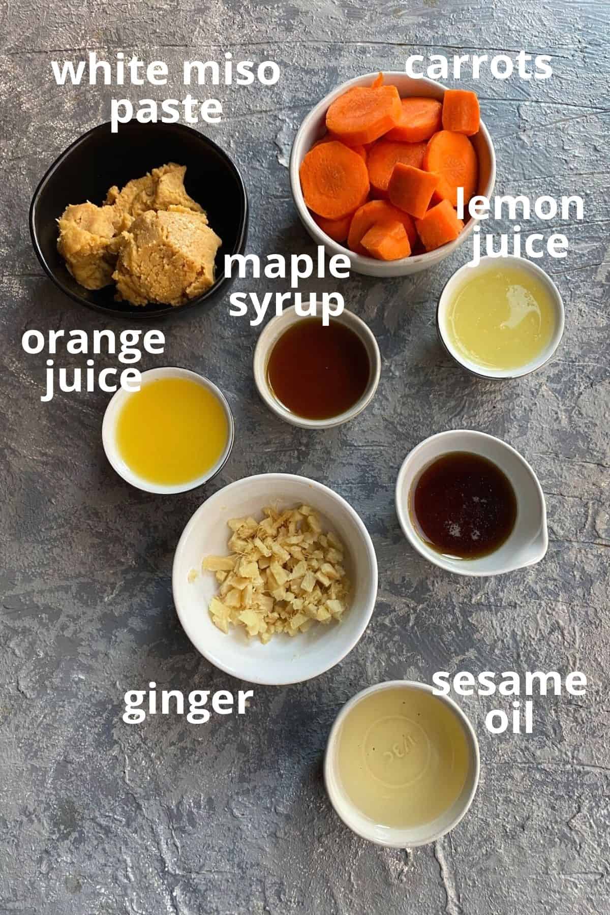 overhead view of the ingredients needed for carrot ginger dressing: carrots, ginger, miso, orange juice, sesame oil and maple syrup