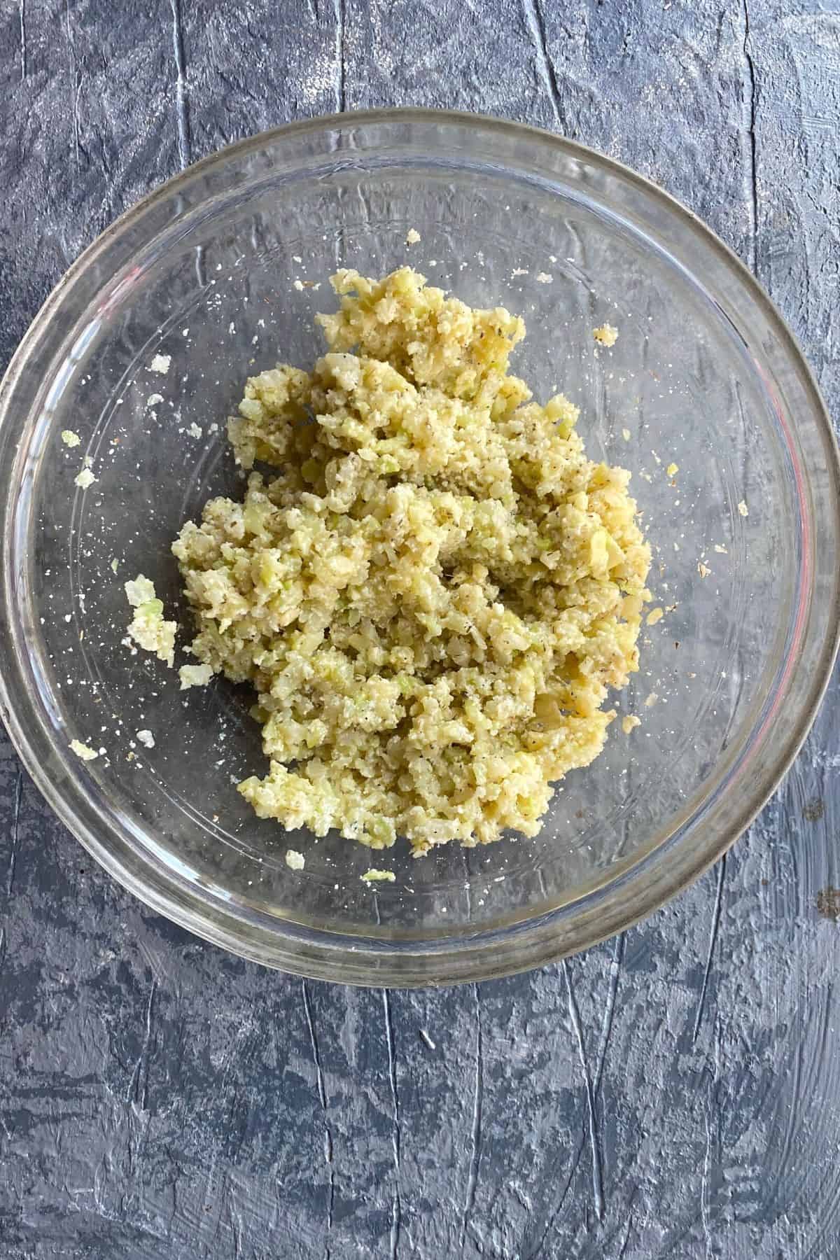 An overhead view of cauliflower rice mixed with Parmesan, seasonings, and egg