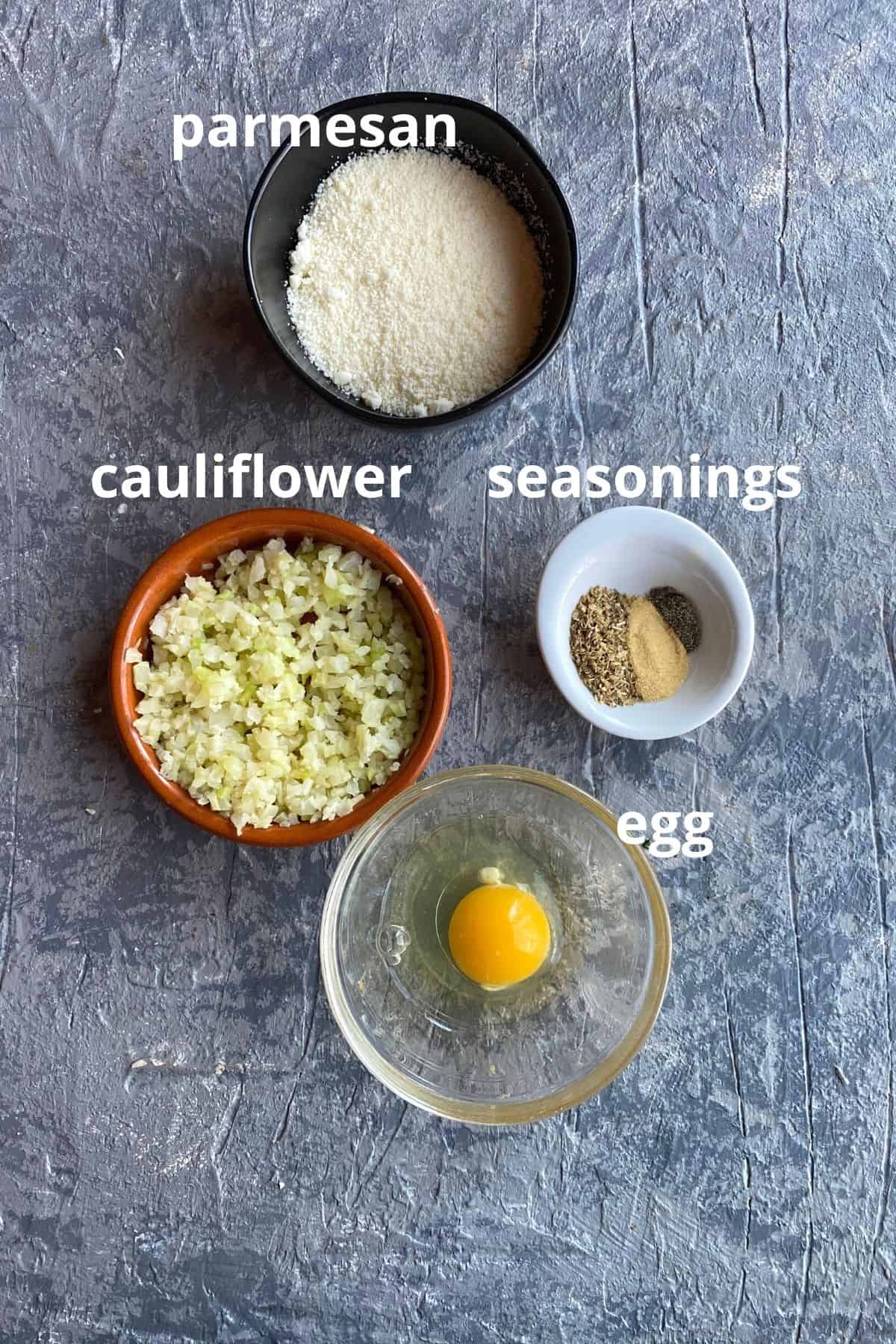 An overhead view of the ingredients to make cauliflower crust pizza; cauliflower, parmesan, seasonings, and egg
