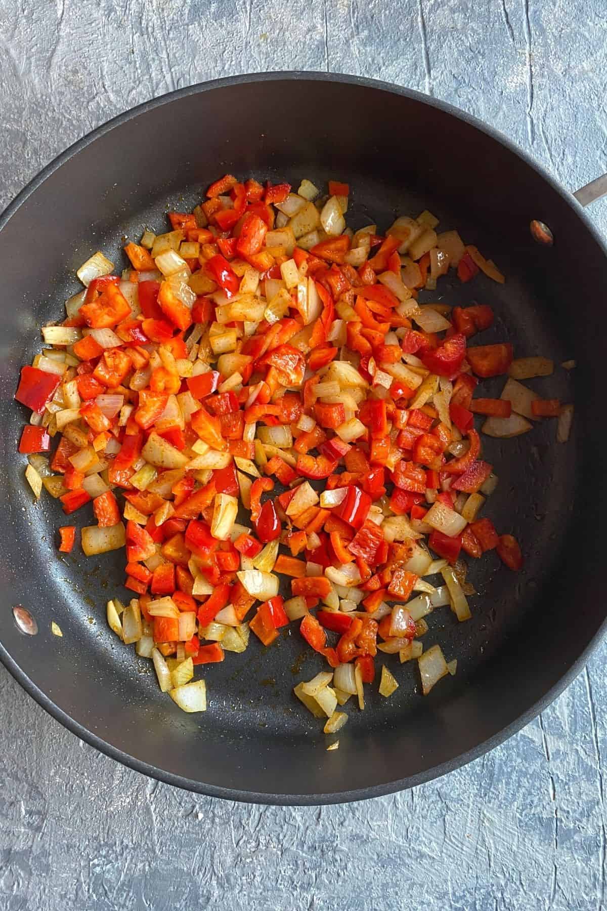 A pan of diced onions, red peppers, and garlic