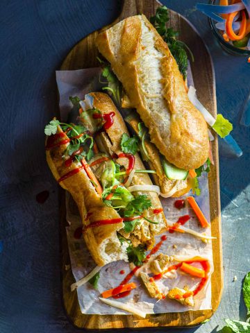 An overhead view of two banh mi sandwiches with sriracha drizzled over the top