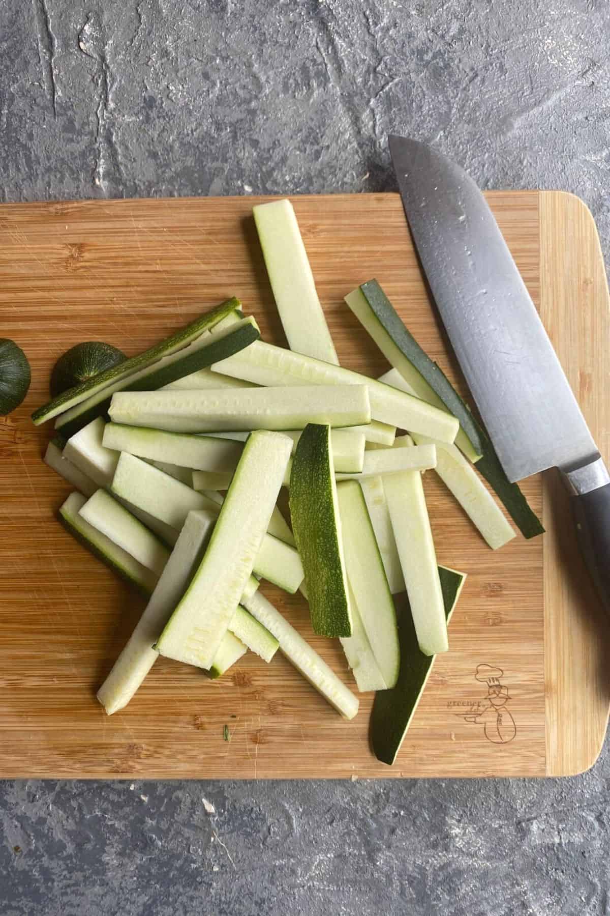 Raw zucchini fry pieces scattered on a cutting board