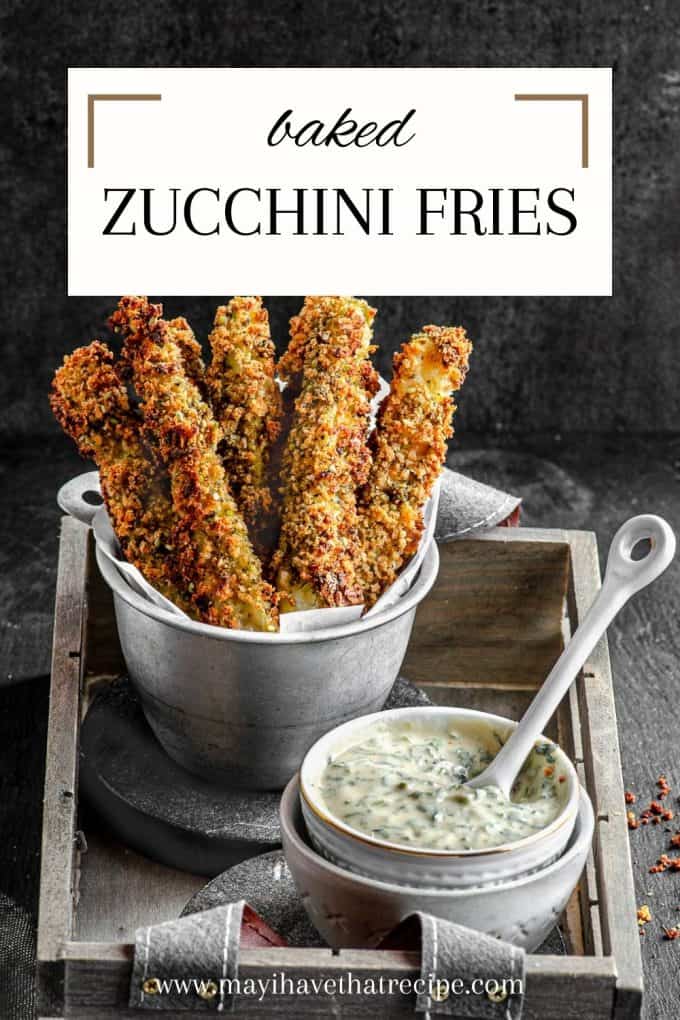 Baked zucchini fries in a fry holder with a small bowl of tahini sauce and a little spoon