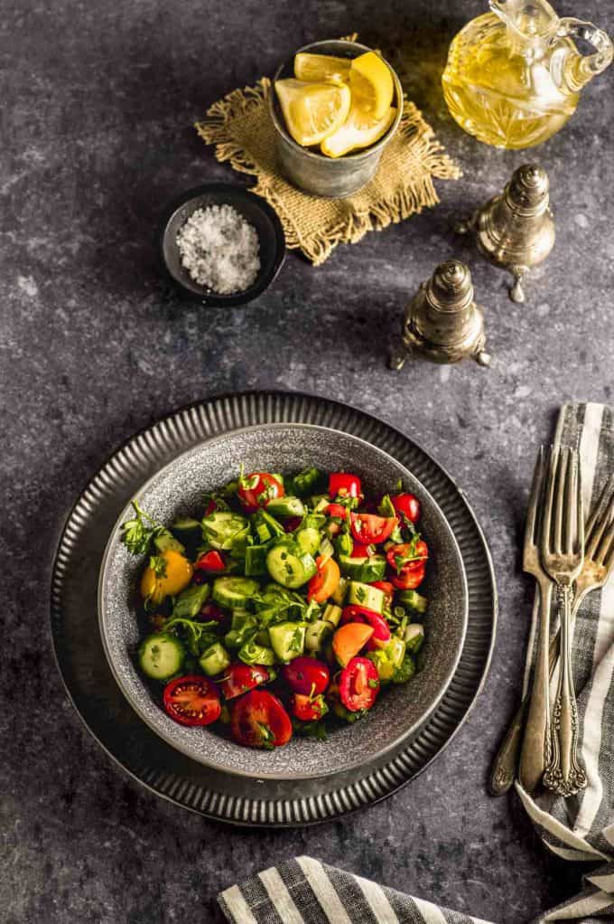 a tables scene of a bowl with tomato cucumber salad