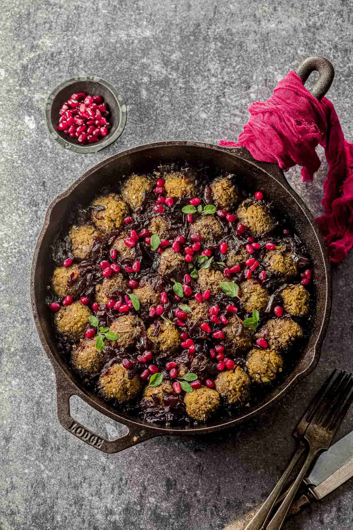 Overhead view of a skillet with eggplant meatballs in pomegranate sauce