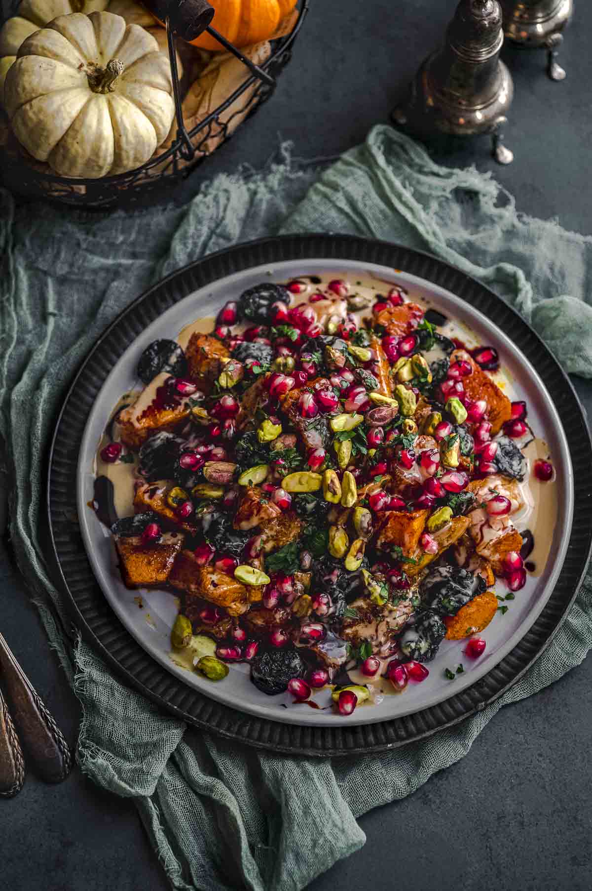 close up view of a plate with roasted butternut squash with tahini, silan, pomegranates and pistachios