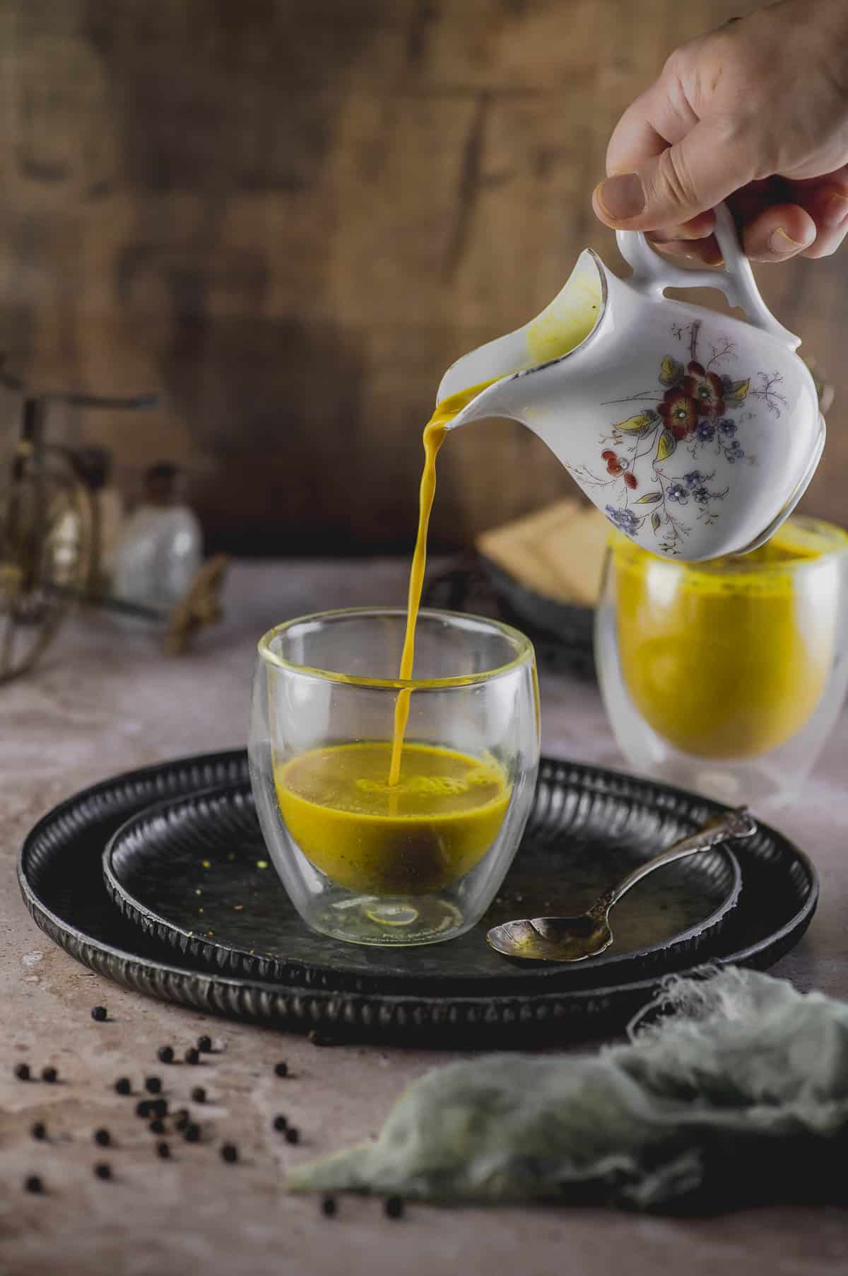 pouring golden milk into a glass cup