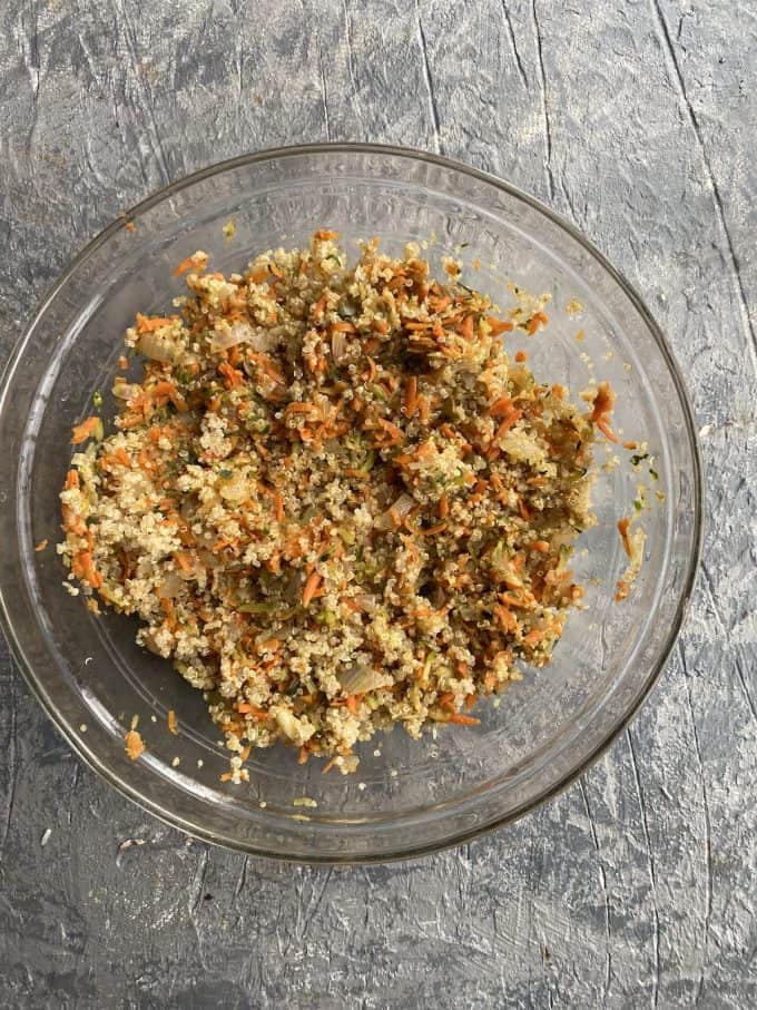 a glass bowl with cooked onions, carrots, zucchini and quinoa