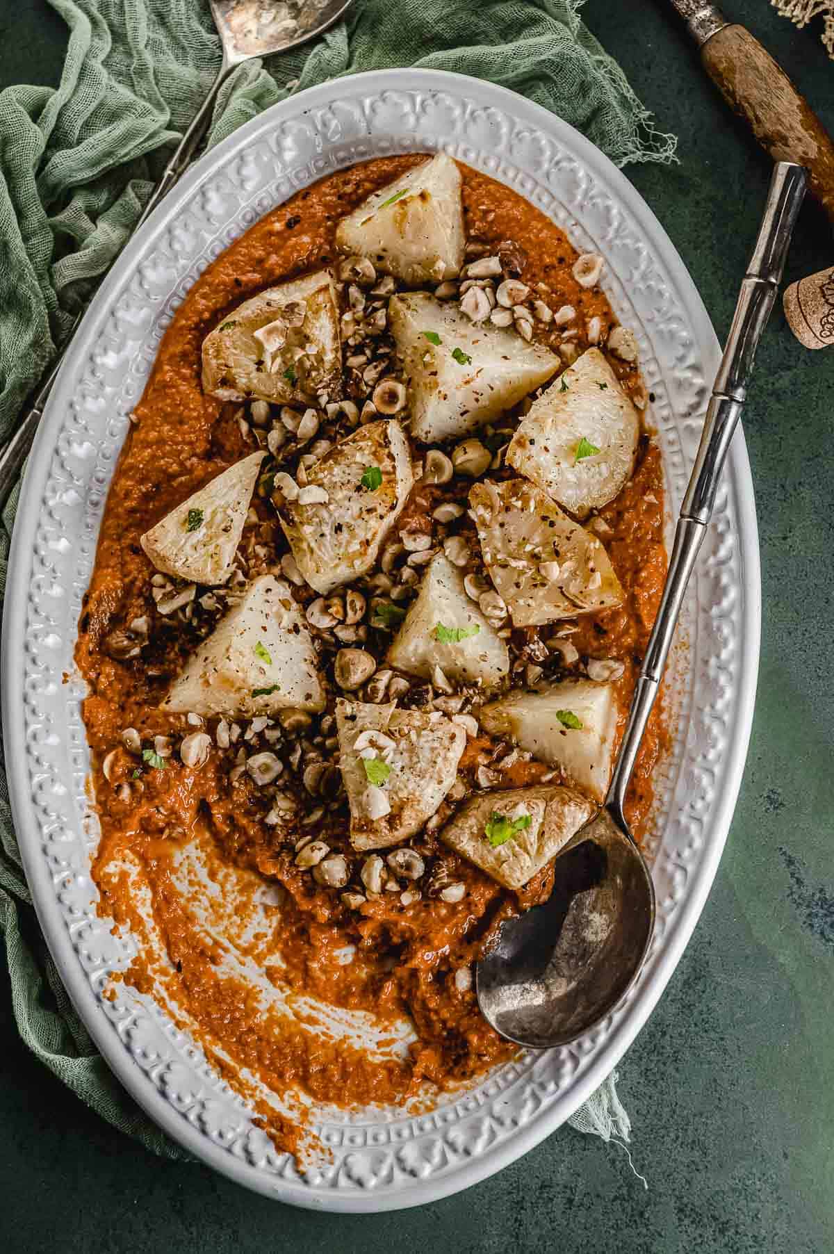 Close up view 
of celery roots wedges on a bed of romesco sauce