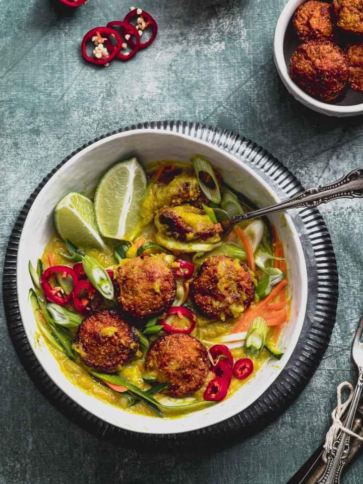 close up view of a bowl of vegan meatballs with some julienne vegetables