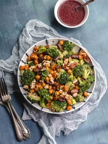 Overhead view of a bowl with broccoli salad next to a bowl with raspberry vinaigrette