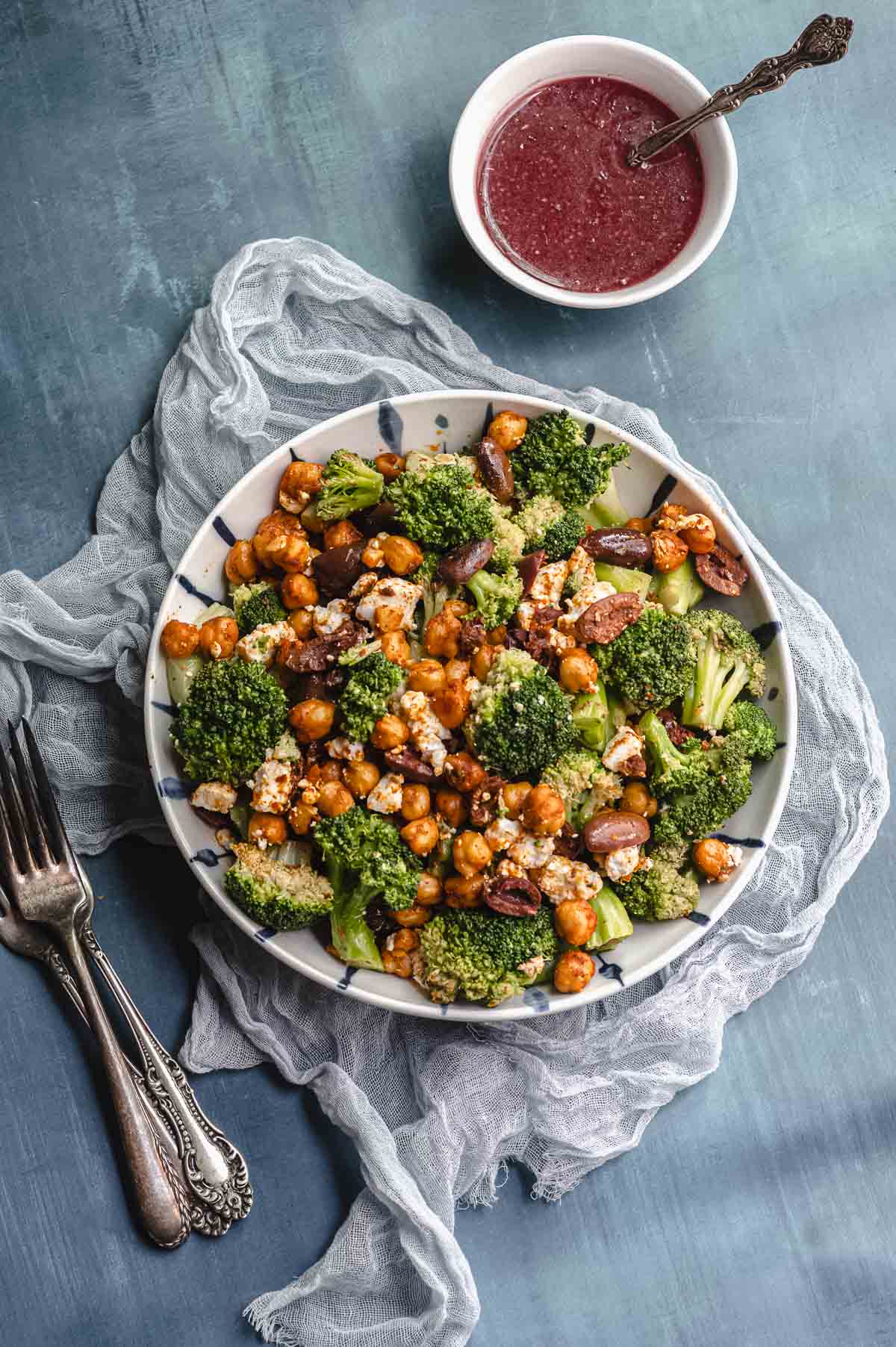 Overhead view of a bowl with broccoli salad next to a bowl with raspberry vinaigrette
