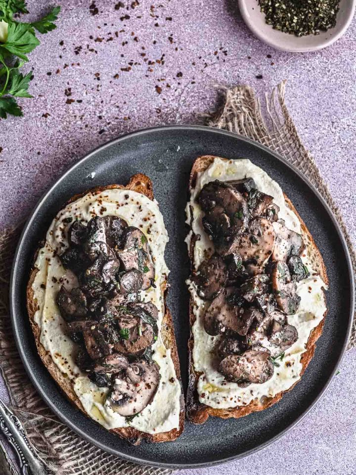 Closeup view of two toast with sautéed mushrooms and hummus