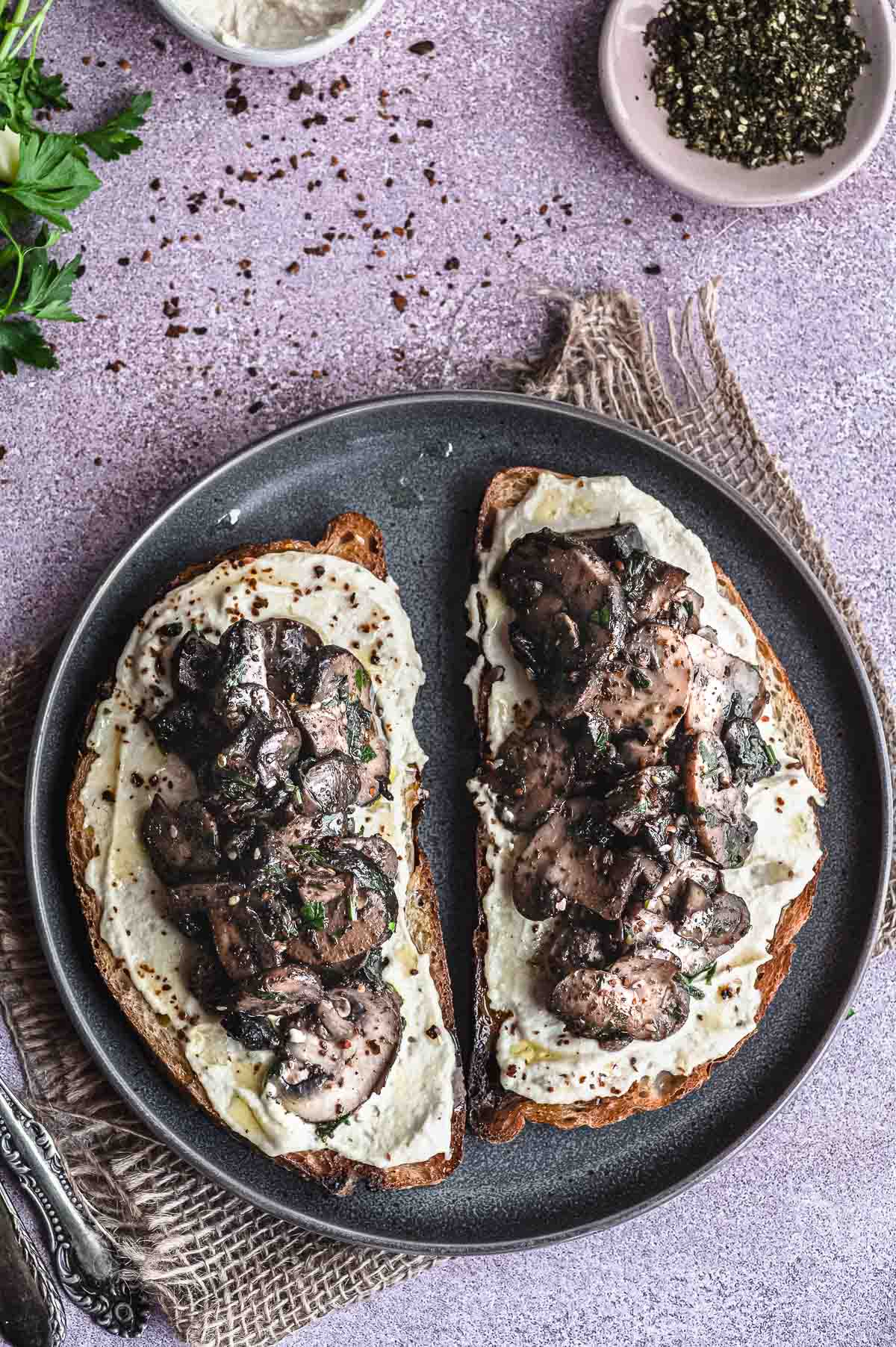 Closeup view of two toast with sautéed mushrooms and hummus

